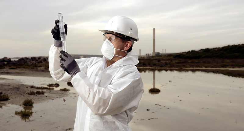 man checking river quality in hazmat suit