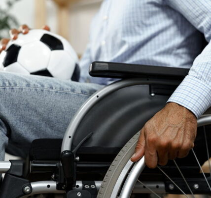 man in wheelchair with football in lap close up