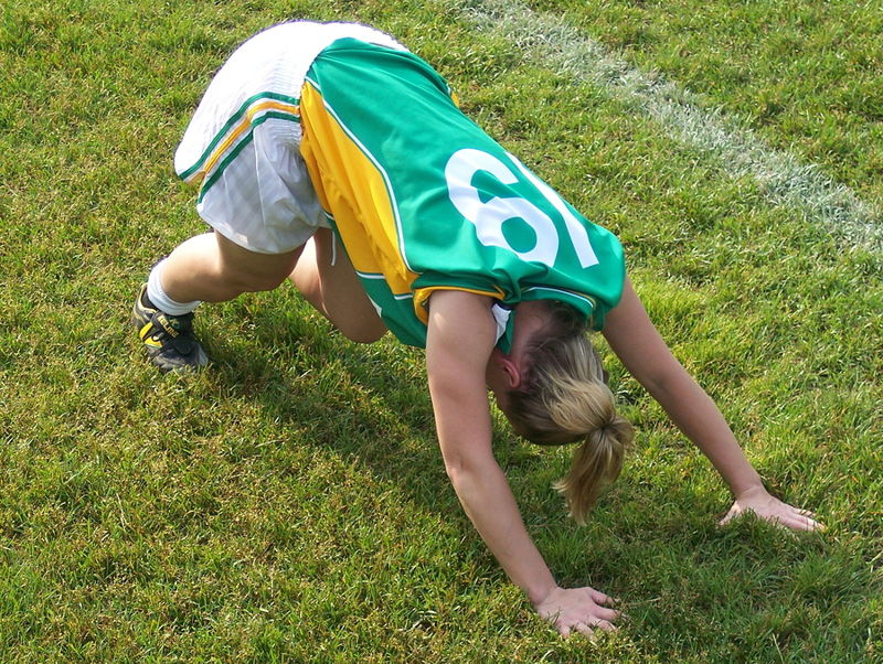woman football player stretching on the pitch