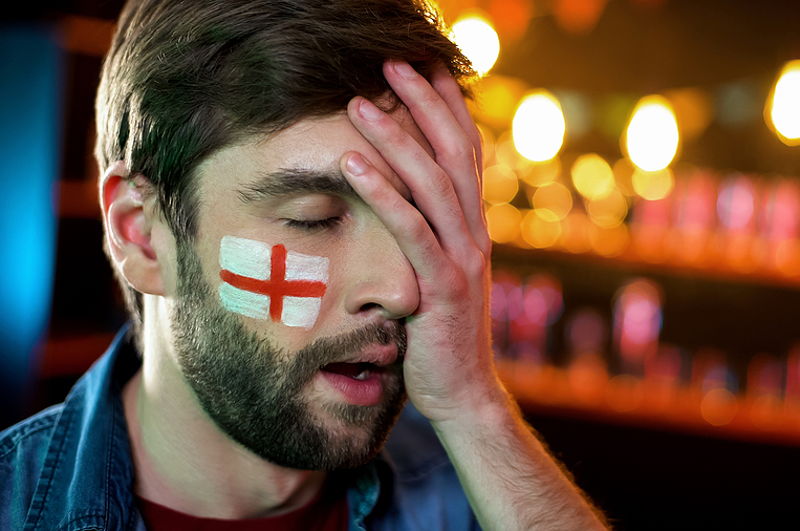 sports fan england flag painted on face sad head in hand